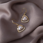 Elegant gold-plated earrings with a unique open-triangle design, adorned with white stones and pearls.